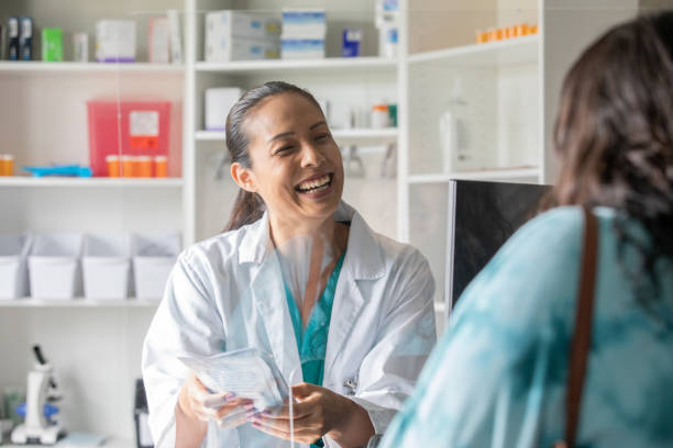 farmaceuta przy kasie uśmiecha się podczas wypełniania recepty dla klienta - checkout counter pharmacy pharmacist patient zdjęcia i obrazy z banku zdjęć