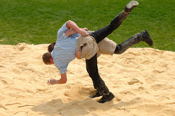 Three legs Two Swiss taking part in a traditional wrestling match (called 'Lutte' or 'Schwingen'). Slight motion blur on the wrestlers' hands and feet. swing stock pictures, royalty-free photos & images