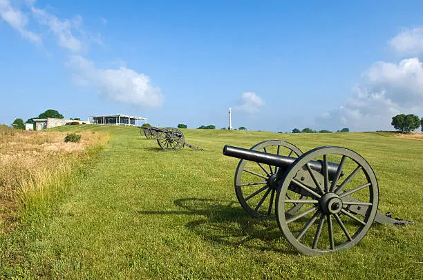 A line of cannon at the Antietam Battlefield in Sharpsburg, Maryland, USA leads to the visitor's center.