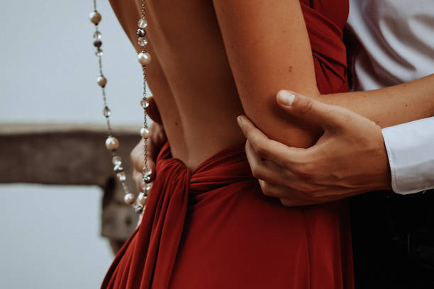 Close-up of a couple hugging Close-up of a young couple in evening wear hugging. Men's hands hug a girl in red. Bare back. woman in red dress stock pictures, royalty-free photos & images