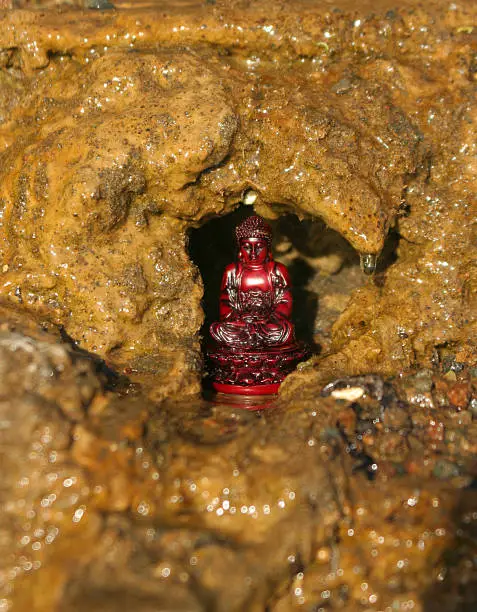 Red statue of Buddha in a cave