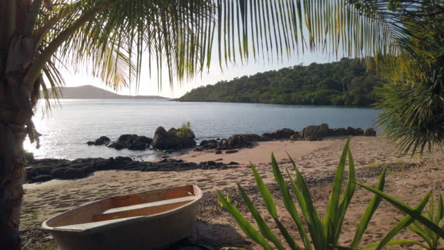 A beautiful beach at late afternoon on a remote tropical island with a small wooden fishing boat
