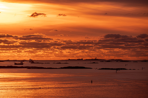 Golden sunset over an archipelago with freight ships waiting for goods.