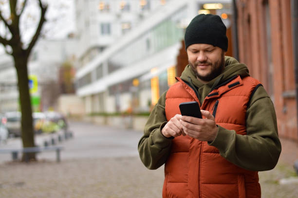 istock Handsome smiling young man dressed casually spending time outdoors at the city, using mobile phone 1442288960