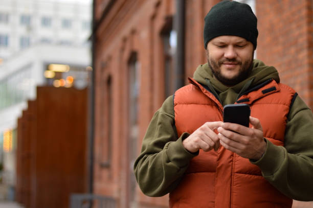 istock Handsome smiling young man dressed casually spending time outdoors at the city, using mobile phone 1442288963