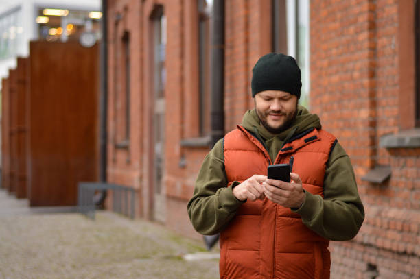 istock Handsome smiling young man dressed casually spending time outdoors at the city, using mobile phone 1442288970