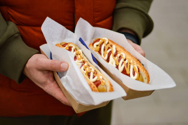 Two grilled french hot dogs in man's hand, fast food and junk food concept, Street food, Two grilled french hot dogs in man's hand, fast food and junk food concept, Street food, hot dog stand stock pictures, royalty-free photos & images