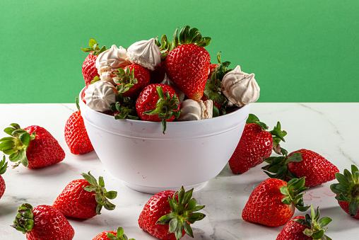 Strawberry dessert with dulce de leche meringue, served in a bowl on a marble background.