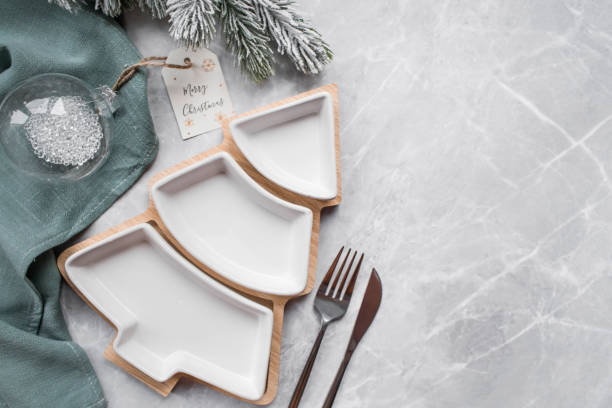 istock Table setting. A plate in the form of a Christmas tree, a green napkin, spruce branches and Christmas decorations on a gray background. The concept of Merry Christmas, New Year 2023 and restaurants. 1442294895