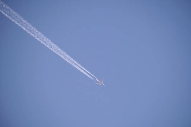 istock Distant passenger jet plane flying on high altitude on clear blue sky leaving white smoke trace of contrail behind. Air transportation concept 1442295426