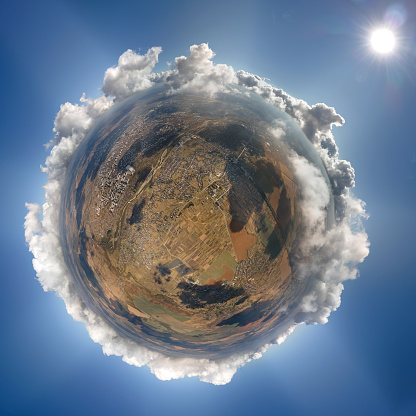 Aerial view from high altitude of little planet earth covered with white puffy cumulus clouds on sunny day.