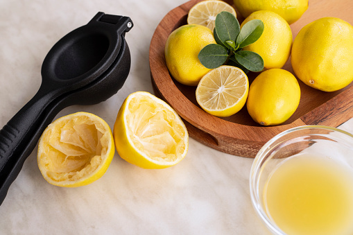 Lemon juicer, lemon juice and lemons on table