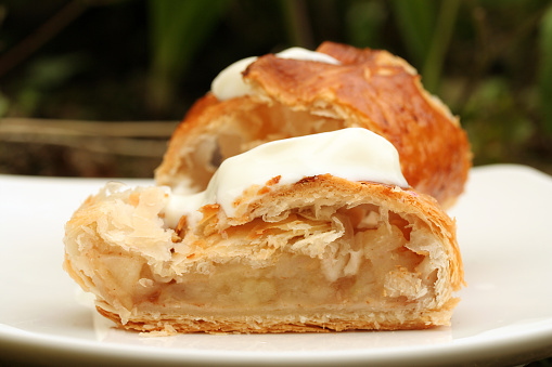 Apple turnover on a white plate werved with cream