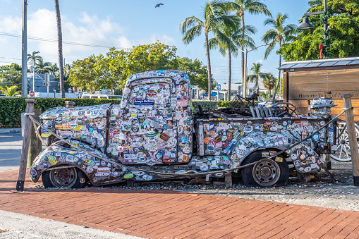 Key West, FL- November 13 2022: Antique Truck covered in Bumper Stickers parked in Key West Florida Giving tourists and businesses a place to put stickers to advertise.