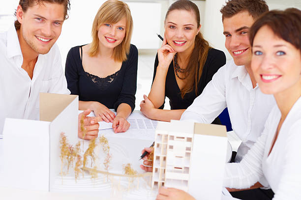 istock Group of architects gathered with architectural models and sketches 144230627