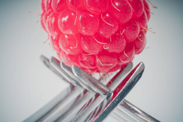 isolated raspberry on two crossing forks on a white background. copy space for text