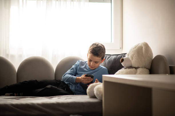 istock Boy alone in his room, playing with parents phone 1442308158