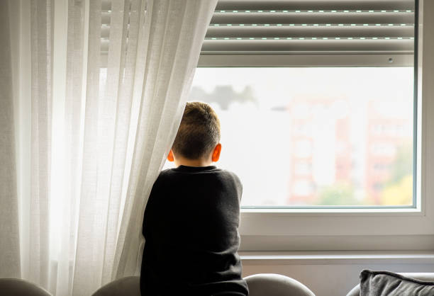 istock Young boy looking through the window, waiting for his parents 1442308584