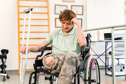 Young military soldier sitting in wheelchair in a rehab center