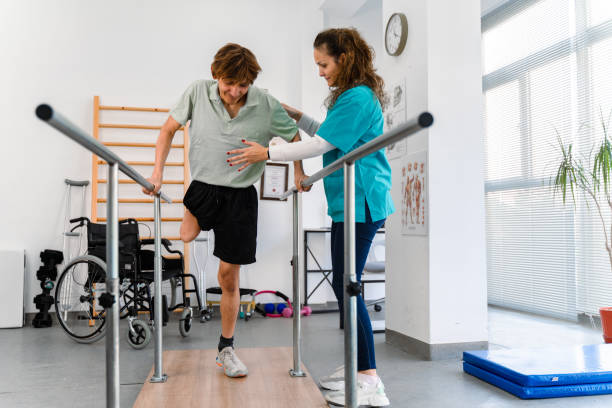 Young man uses parallel bars in a rehab center