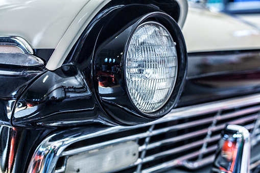 Close-up detail shot of the headlight on a classic collector's car late 1950's (1957) convertible.