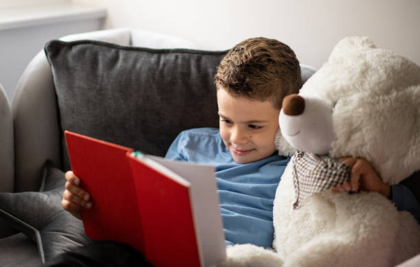 istock Cute young boy reading a book to his teddy bear 1442313834