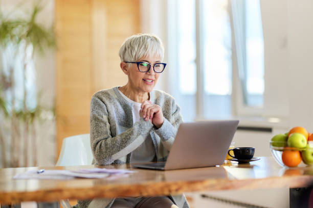 istock Happy senior woman using computer at home. 1442314407