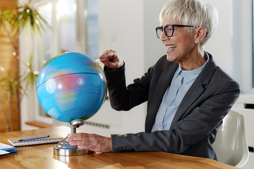 Happy female entrepreneur examining the globe while working in the office. Blurred motion.