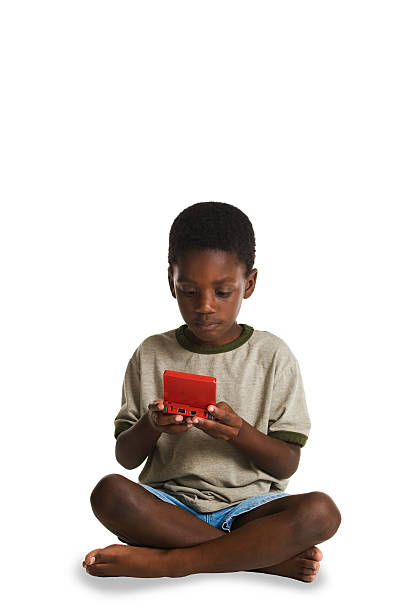 A young, African American boy playing an electronic game. This image is one of a series of conceptual images isolated on white backgrounds.