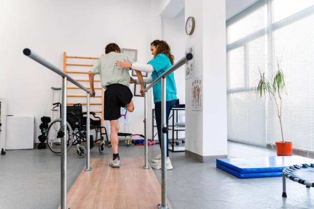 istock Young man uses parallel bars in a rehab center 1442316317