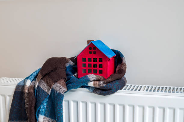 istock House model wrapped in scarf on closed radiator, space for text. Winter heating efficiency 1442316663