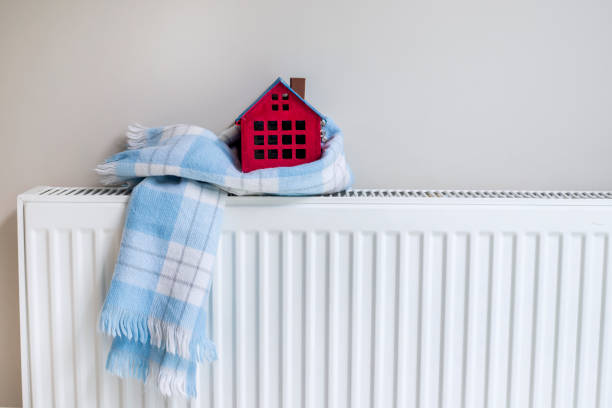 istock House model wrapped in scarf on closed radiator, space for text. Winter heating efficiency 1442316665