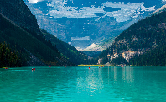 Canoeing in the turquoise waters of Lake Louise at midday before Mt Victoria and its glacier.