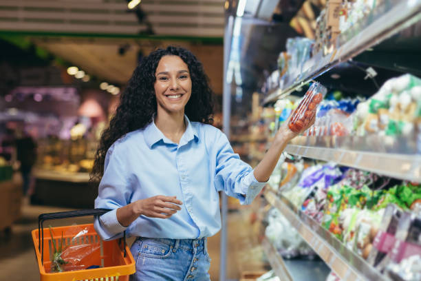 Portrait of beautiful vegetarian woman in supermarket, Latin American woman chooses vegetables for dinner, smiling and looking at camera Portrait of beautiful vegetarian woman in supermarket, Latin American woman chooses vegetables for dinner, smiling and looking at camera. reduction looking at camera finance business stock pictures, royalty-free photos & images