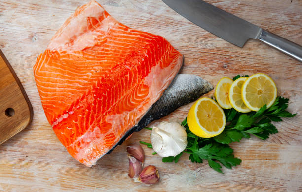 istock Appetizing raw salmon fillet with lemon and greens 1442318454