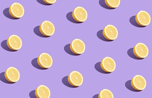 Lemon slice creative pattern on  purple background. Yellow trendy color food. Summer fruits creative layout.