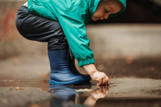istock Happy boy playing outside on a rainy day wearing rubber boots and jacket 1442322327