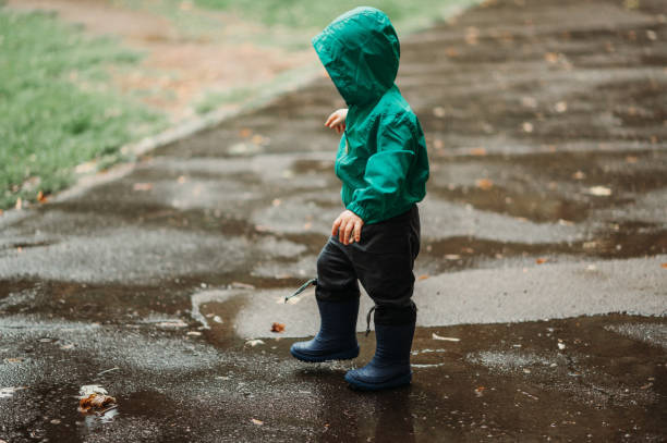 istock Happy boy playing outside on a rainy day wearing rubber boots and jacket 1442322328
