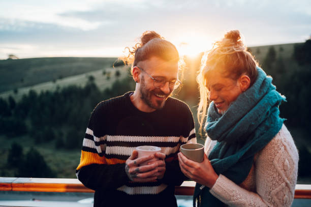 istock Young couple drinking coffee or tea while standing on their balcony at sunrise 1442322330