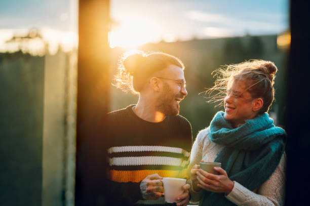 istock Young couple drinking coffee or tea while standing on their balcony at sunrise 1442322338