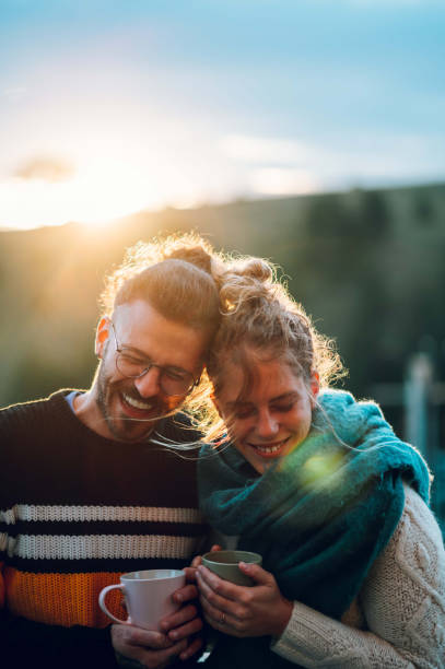 istock Young couple drinking coffee or tea while standing on their balcony at sunrise 1442322340