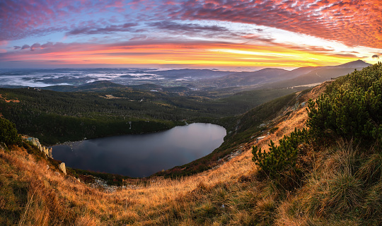 Scenic autumn sunrise in mountains. Colorful morning sky over hills lit by sun. Karkonosze National Park in Poland. Picturesque autumn landscape.