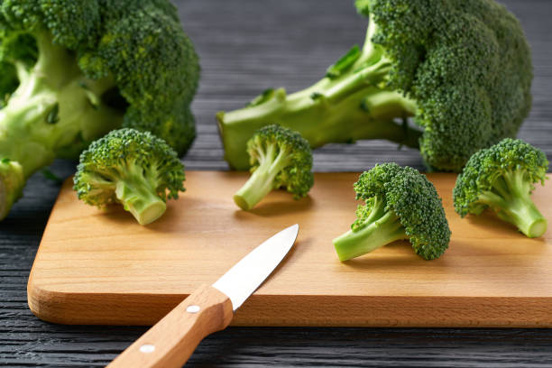 istock Cooking healthy food, cutting broccoli for baking on a dark table. 1442331057