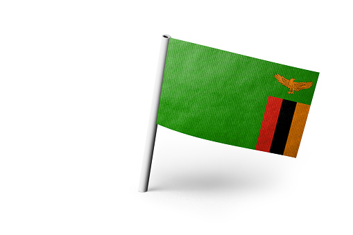 Small paper flag of Zambia pinned. Isolated on white background. Horizontal orientation. Close up photography. Copy space.