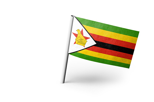 Small paper flag of Zimbabwe pinned. Isolated on white background. Horizontal orientation. Close up photography. Copy space.