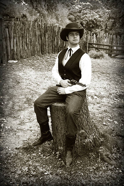 istock Black and White Gunslinger Cowboy Posing on Stump with Gun 144233571