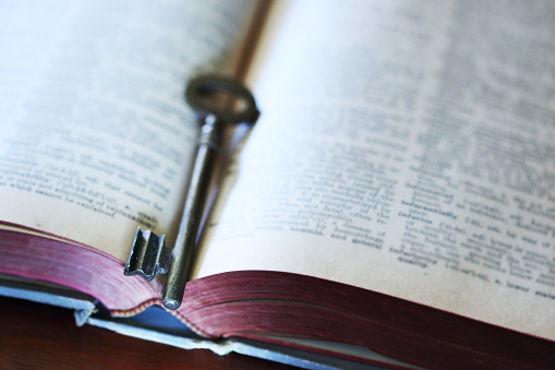 An old key rests inside an old book. Photographed with a very shallow depth of field.