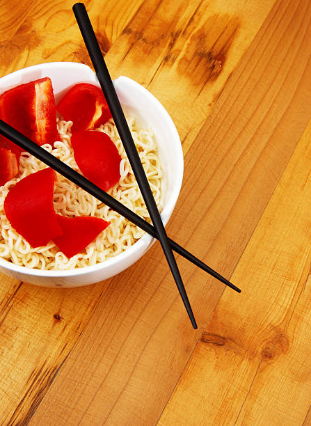 A woman holding chopsticks and a bowl filled with cucumber salad or oi muchim. The cucumbers are sliced, tossed in a mix of chili flakes, oil, and soy sauce. Spicy and savory dish. Selective focus.