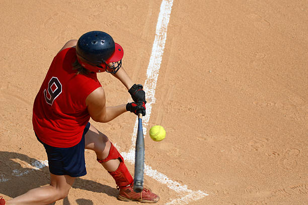 A man at a sports pitch playing softball Young lady on a High School softball team swinging at the ball. baseline stock pictures, royalty-free photos & images