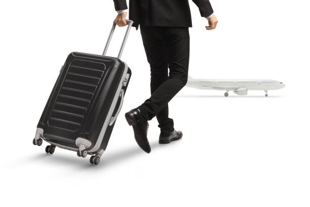 istock Rear view shot of a man pulling a suitcase and walking towards a plane 1442361874